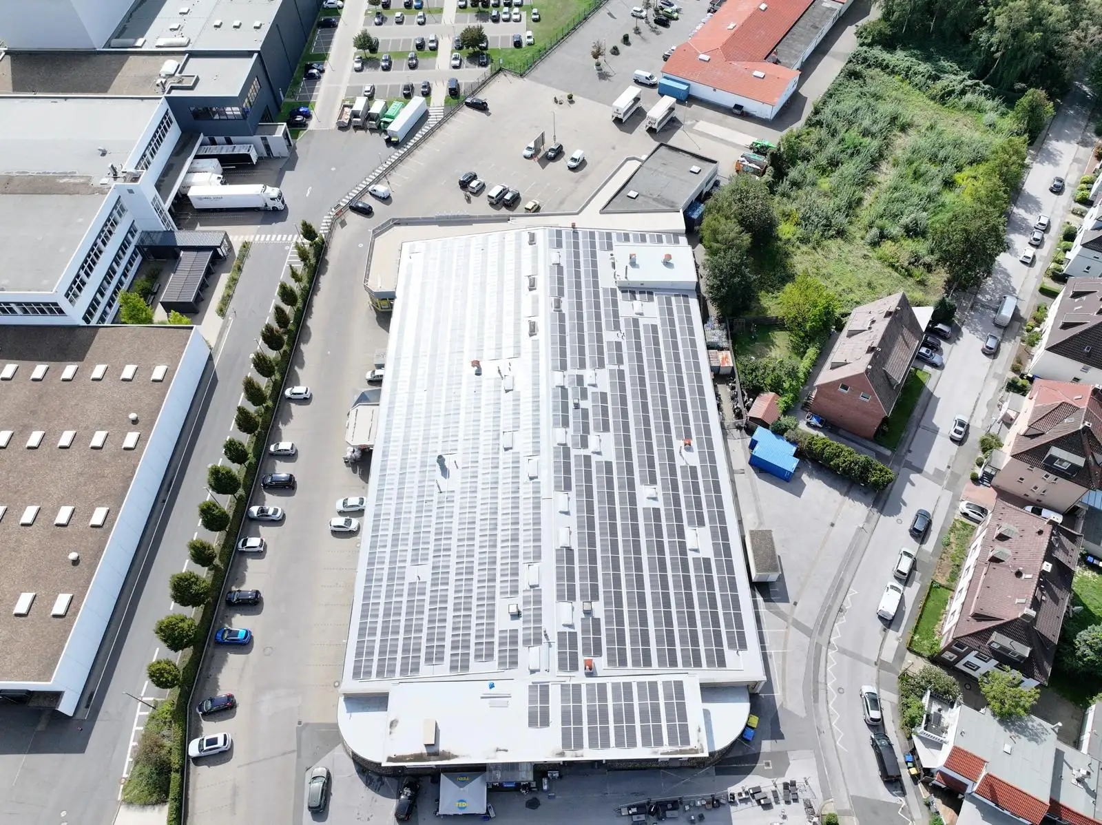 Luftbild einer Gewerbehalle mit flexiblen Photovoltaik-Modulen auf dem Flachdach